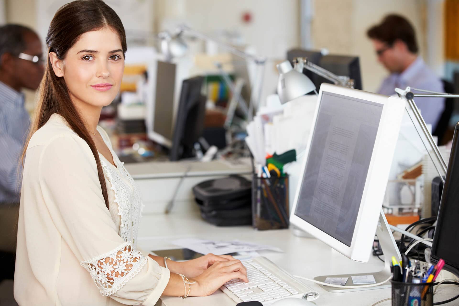 woman working at desk in busy creative office P4PWZHR